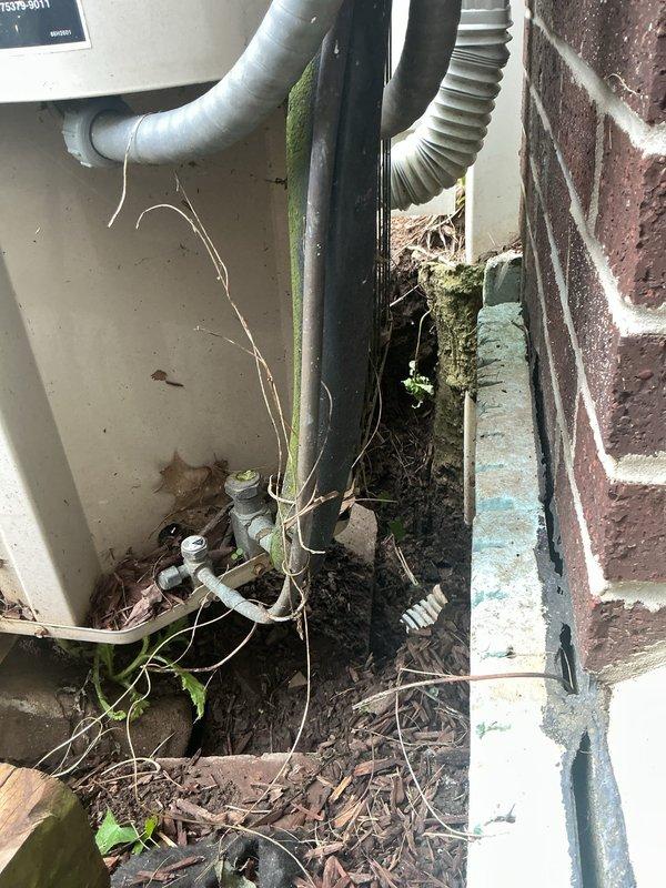 Responded to service call for broken underground downspout drainage pipe located at rear left side of property near fence line. Conducted on-site assessment and documented conditions, including HVAC unit settling issues potentially related to drainage problems. Provided free estimate for repair or replacement of damaged underground drainage system, with photographic documentation of affected areas showing debris accumulation and vegetation growth around exterior mechanical equipment.