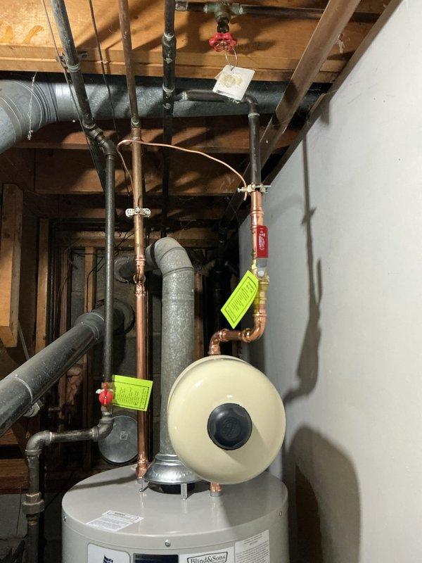 Installed a new 40-gallon tall residential water heater with a 10-year warranty in basement utility room. Installation included a ball valve shut-off, white expansion tank mounted on copper supply lines, and proper electrical bonding for code compliance. Removed and hauled away the existing water heater as requested, staged all necessary components from shop inventory, and completed all copper pipe connections with soldered joints. System was pressure tested, all safety valves verified operational, and unit commissioned successfully with no leaks detected.