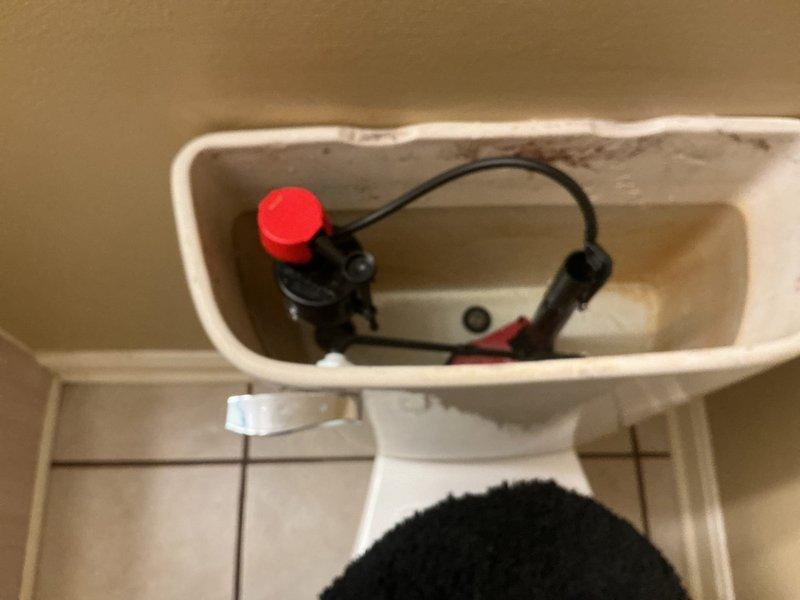 Responded to service call for upstairs toilet leaking into ceiling below. Upon arrival, performed diagnostic inspection of toilet and surrounding plumbing fixtures. Inspected toilet tank internal components including fill valve assembly with red cap, flush valve mechanism, and associated supply lines. Examined flexible braided stainless steel supply line connection from wall-mounted shut-off valve to toilet. Identified source of water leak and documented conditions with photographs. Completed diagnostic evaluation of plumbing system to determine cause of ceiling leak and necessary repairs.