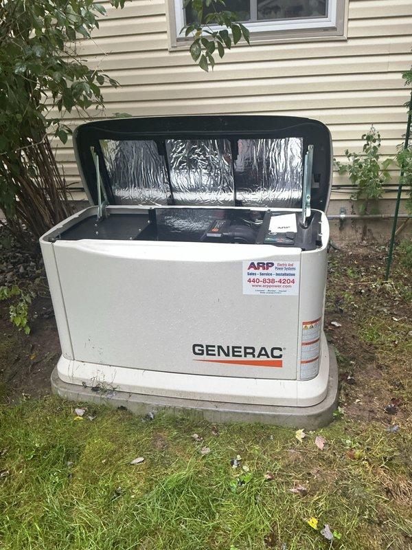 Performed routine maintenance on a Generac Guardian 22kW standby generator unit. Accessed interior components by opening top panel, inspected electrical connections, control switches, and circuit breakers for proper operation. Verified mechanical components and wiring integrity throughout the system. Unit exterior showed normal weathering consistent with outdoor installation on concrete pad. All components found functioning within manufacturer specifications upon completion of scheduled maintenance procedure.