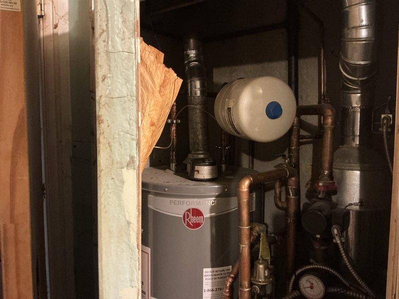 Evaluated existing 16-year-old boiler system and utility closet configuration for potential conversion from hydronic heating to forced air HVAC system. Assessed attic accessibility via pull-down ladder for ductwork installation feasibility and documented current mechanical room layout including water heater, electrical panel, and existing piping infrastructure to provide comprehensive system replacement estimate.
