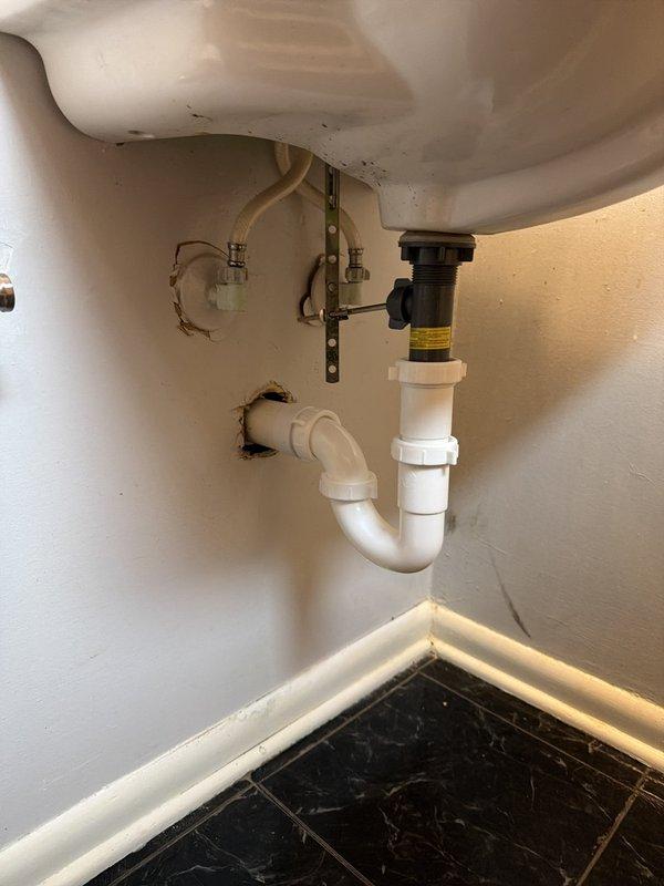 Replaced deteriorated cast iron drain piping for double lavatory system by opening walls on both sides of the drain assembly. Cut and removed existing cast iron pipe above the vent down past the long sweep 90-degree fitting. Installed new PVC drainage piping from the cut point downward, transitioning from PVC to existing cast iron using code-approved no-hub transition bands. Installed new P-trap assemblies at both sink locations to complete the drainage system upgrade.