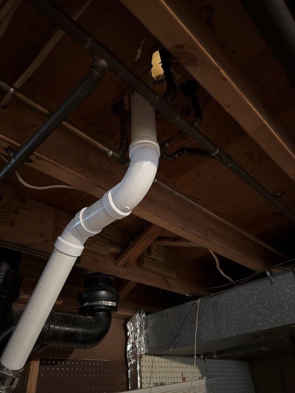 Replaced deteriorated cast iron drain piping for double lavatory system by opening walls on both sides of the drain assembly. Cut and removed existing cast iron pipe above the vent down past the long sweep 90-degree fitting. Installed new PVC drainage piping from the cut point downward, transitioning from PVC to existing cast iron using code-approved no-hub transition bands. Installed new P-trap assemblies at both sink locations to complete the drainage system upgrade.