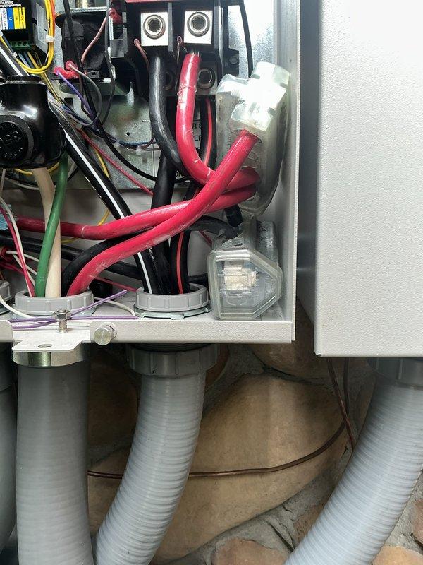 Corrected electrical installation deficiencies identified during failed inspection of transfer switch system. Properly seated red wires fully under terminal lugs, ensured all conductors were stripped and inserted completely into clear tap connectors, and secured conduit runs with appropriate strapping. Sealed all LB conduit bodies and sealtight fittings to prevent air transfer into garage disconnects, bringing installation into compliance with electrical code requirements.