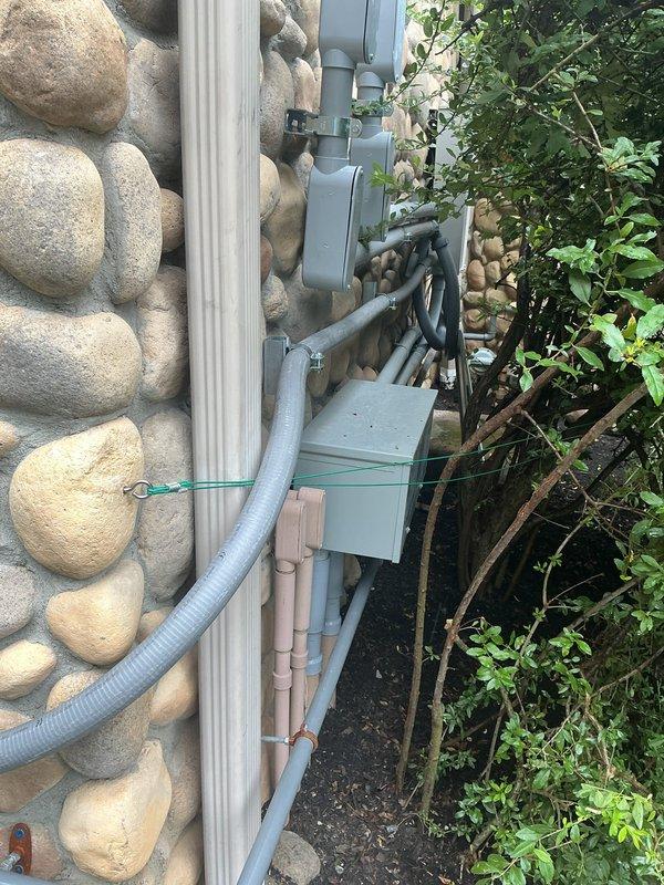 Corrected electrical installation deficiencies identified during failed inspection of transfer switch system. Properly seated red wires fully under terminal lugs, ensured all conductors were stripped and inserted completely into clear tap connectors, and secured conduit runs with appropriate strapping. Sealed all LB conduit bodies and sealtight fittings to prevent air transfer into garage disconnects, bringing installation into compliance with electrical code requirements.