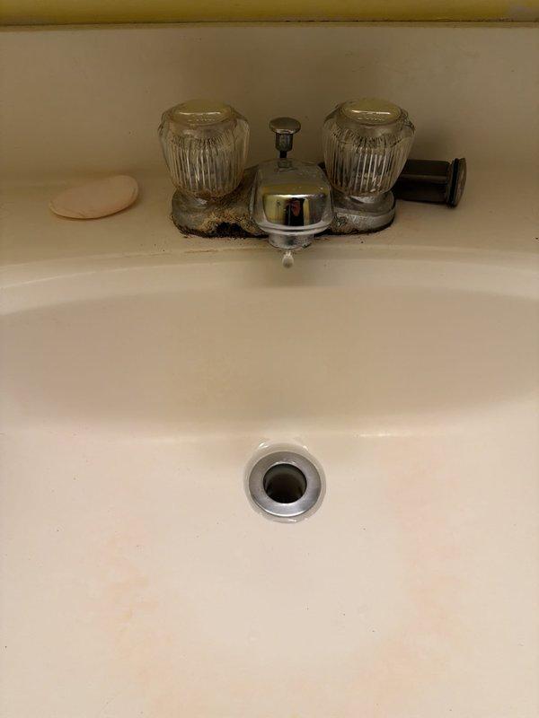 Replaced bathroom sink faucet assembly, removing old two-handle fixture with corroded chrome bases and significant mineral buildup. Installed new faucet hardware with proper connections to existing supply lines and drain assembly. Verified all connections for proper operation and absence of leaks beneath sink.