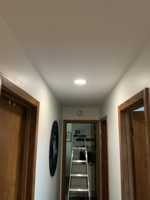 Completed comprehensive lighting upgrade and electrical troubleshooting throughout residence. Installed six 6-inch wafer lights in living room with new single-pole dimmer switch, requiring upgrade from single-gang to two-gang box. Removed existing hallway light fixture and replaced with 6-inch wafer light controlled by new dimmer switch. Replaced kitchen sink can light with 8x8 fixture. Performed two hours of diagnostic troubleshooting to identify and repair non-functioning switched outlet in family room following previous device replacements. Removed five closet pull-chain fixtures and installed 6-inch motion sensor wafer lights, including installation of old work boxes where necessary to accommodate proper fixture placement. Work required drilling access holes and selective drywall cutting for wire routing and box installations. All customer-provided fixtures installed per manufacturer specifications with proper electrical connections and switch controls.
