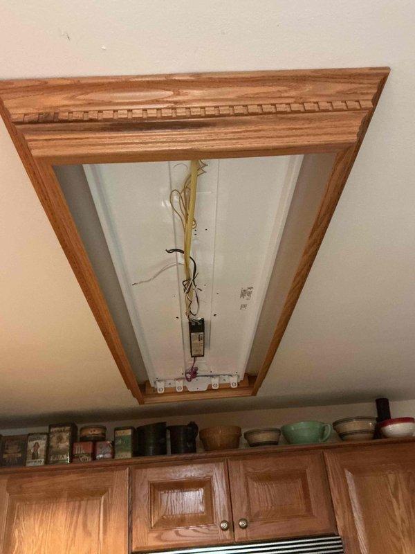 Responded to service call for assistance with fluorescent bulb installation in kitchen ceiling fixture. Customer was unable to access fixture due to mobility limitations with ladder use. Utilized customer-provided step ladder to safely access recessed ceiling-mounted fluorescent light fixture with decorative wood trim surround. Removed fixture cover to expose fluorescent lamp sockets and ballast assembly. Installed new fluorescent tubes into multi-socket fixture, ensuring proper seating and electrical contact. Verified ballast operation and confirmed all lamps illuminated correctly upon energizing circuit. Reinstalled fixture cover and secured all components. Fixture restored to full operational status.