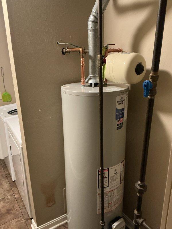 Removed existing water heater and installed new 40-gallon Bradford White residential water heater. Upgraded installation to current code compliance by installing new ball valve shut-off and thermal expansion tank. Connected copper supply lines and verified proper venting with existing flue system. Confirmed unit bonding and shut-off valve met code requirements. Completed all plumbing connections, tested system for proper operation and leak-free performance. Hauled away old water heater from premises. Registered new unit with manufacturer for 6-year warranty coverage.