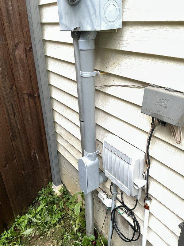 Replaced damaged exterior electrical conduit running from meter box to main electrical panel. Installed new PVC conduit pipe with proper couplings and mounting straps, then pulled and terminated new circuit wiring to restore safe electrical service to the panel.