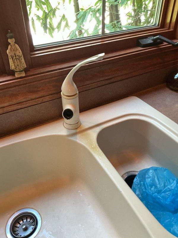 Installed customer-supplied kitchen faucet at double-basin sink, replacing existing beige single-handle unit. Verified proper connection to existing supply lines and tested for leaks, with under-sink plumbing including garbage disposal and shutoff valves remaining functional throughout installation.