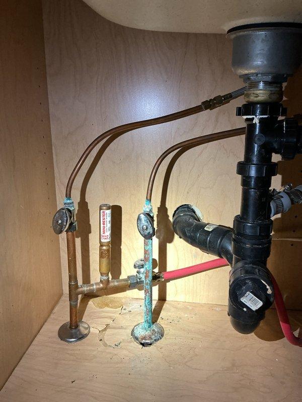 Installed customer-supplied kitchen faucet at double-basin sink, replacing existing beige single-handle unit. Verified proper connection to existing supply lines and tested for leaks, with under-sink plumbing including garbage disposal and shutoff valves remaining functional throughout installation.