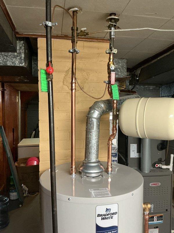 Successfully replaced existing water heater with a new Bradford White 40-gallon short model in basement utility area. Installation included a new shut-off valve and expansion tank to ensure proper system operation and code compliance. Connected all copper supply lines to the unit's inlet and outlet ports, securing proper water flow throughout the residential plumbing system. The expansion tank was mounted horizontally adjacent to the water heater to accommodate thermal expansion and protect the system from excess pressure. All connections were tested for leaks and proper operation. Unit comes with a 6-year tank warranty for customer protection.