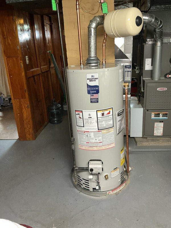 Successfully replaced existing water heater with a new Bradford White 40-gallon short model in basement utility area. Installation included a new shut-off valve and expansion tank to ensure proper system operation and code compliance. Connected all copper supply lines to the unit's inlet and outlet ports, securing proper water flow throughout the residential plumbing system. The expansion tank was mounted horizontally adjacent to the water heater to accommodate thermal expansion and protect the system from excess pressure. All connections were tested for leaks and proper operation. Unit comes with a 6-year tank warranty for customer protection.