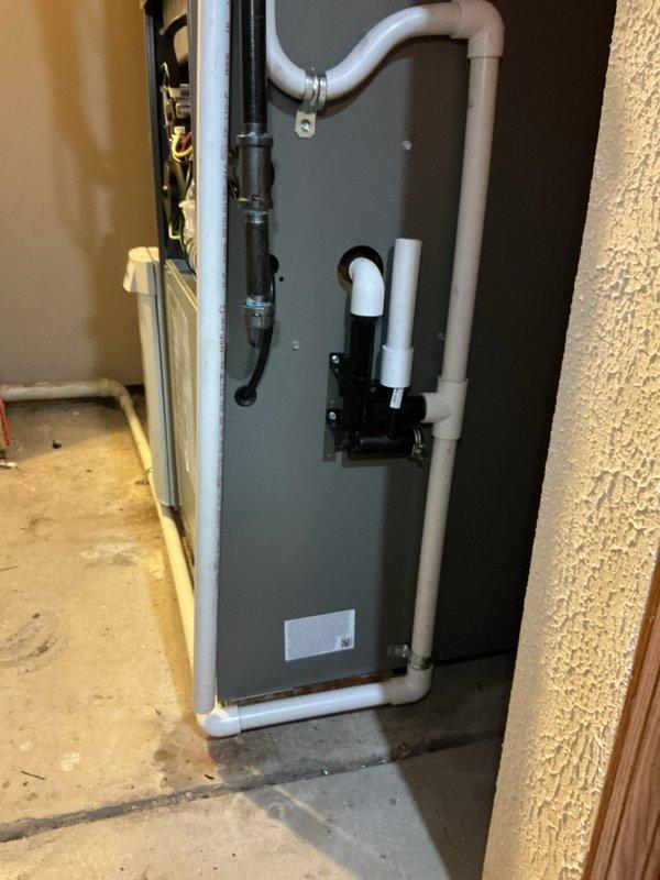 Completed full HVAC system installation including a new 90% efficiency furnace/air handler unit with integrated humidification system. Installed vertical air handler in garage utility area with proper electrical connections, condensate drainage system using PVC piping, and black condensate pump components mounted to unit face. Added AprilAire whole-home humidifier with dedicated water supply line and integrated ductwork connections using flexible metallic ducting with spiral-wrapped insulation tape. All electrical wiring, conduit, and low-voltage control circuits properly installed and terminated. System tested and operational upon completion.