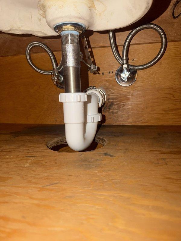 Replaced hall bathroom lavatory faucet with new chrome single-handle unit and installed new angle stops for improved water shutoff capability. Repaired drain assembly at wall connection, including installation of new P-trap and drain components to ensure proper drainage and eliminate leaks. All plumbing connections were tested and verified operational upon completion.