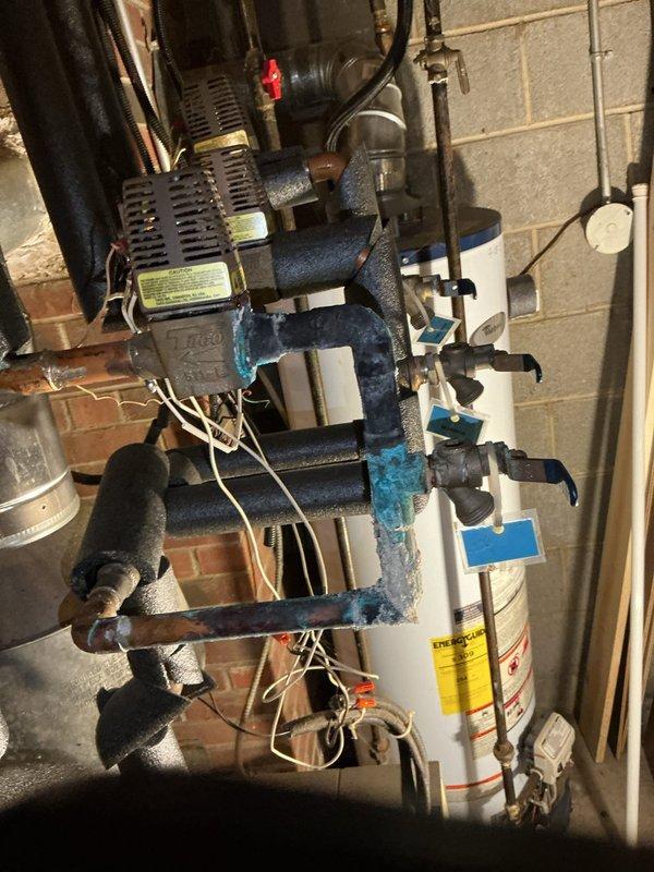 Responded to no-heat call for boiler system that would not fire. Upon arrival, performed diagnostic inspection of heating system including circulator pump assembly, piping connections, and associated components. Identified heavily corroded tee-joint fitting with rust deterioration that was compromising system integrity and potentially affecting proper boiler operation. Documented existing conditions of blue circulator pump unit showing age-related wear, multiple zone valves, copper and black iron piping connections, and expansion tank. System evaluation revealed maintenance concerns requiring attention to restore reliable heating operation.