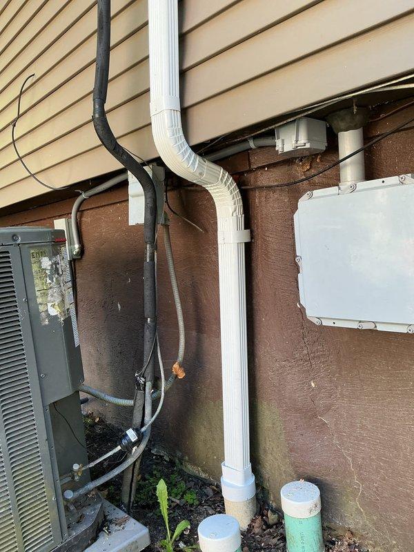 Completed electrical estimate and assessment for AC circuit rewiring at residential property. Evaluated exterior electrical infrastructure including existing gray junction box, black and white PVC conduit runs with elbow joints, and weatherproof electrical boxes mounted on building exterior with vinyl siding. Documented current wiring configuration showing black electrical cables connecting to panel and following conduit pathways along exterior wall. Assessed interior electrical requirements in room with popcorn textured ceiling, identifying potential access points and routing options for new circuit installation. Photographed existing conditions of both exterior utility infrastructure and interior spaces to provide comprehensive documentation for rewiring scope and material requirements.