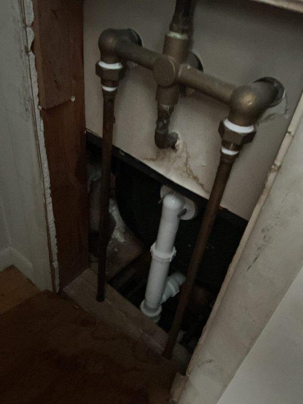 Responded to service call for insufficient hot water delivery and improper temperature mixing at bathtub fixtures. Upon inspection, found 15-year-old tanked water heater with inadequate hot water output requiring extreme faucet adjustment to achieve desired temperature. Assessed supply line configuration and shut-off valve operation at water heater connection point. Evaluated three-handle tub faucet assembly showing signs of internal cartridge wear and improper hot/cold water balancing. Documented existing plumbing infrastructure including copper supply lines and PVC drainage system. Recommended water heater replacement due to age and declining performance, along with potential faucet valve servicing to restore proper temperature control and mixing function.