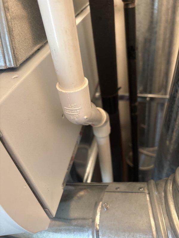HVAC installation failed initial inspection due to improper condensate line routing from Aprilaire humidifier making contact with flue pipe, creating a safety hazard. Documented code violation with photographic evidence showing PVC condensate drain line positioned too close to exhaust flue in mechanical space. Job placed on hold pending manager approval for corrective action and re-routing of condensate line to maintain proper clearance from high-temperature flue pipe per manufacturer specifications and local building codes.