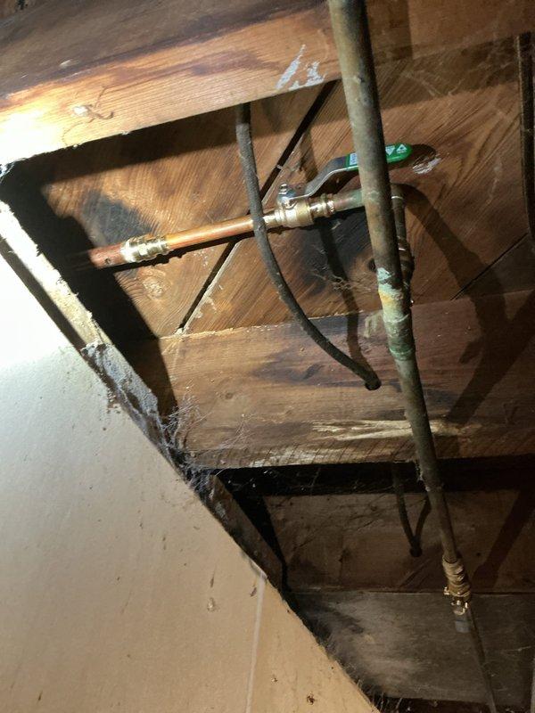 Responded to service call for two non-functional outdoor spigots with active leaks occurring inside the residence. Located leak sources in attic/ceiling cavity where supply lines fed exterior hose bibs. Accessed crawl space and identified failed connections and deteriorated fittings on copper supply lines serving both spigots. Replaced defective ball valve assembly with blue-handled brass valve, repaired compromised pipe connections, and secured all plumbing runs within ceiling framework. Tested system under full pressure to verify leak elimination and restored water service to both outdoor spigots for normal operation.