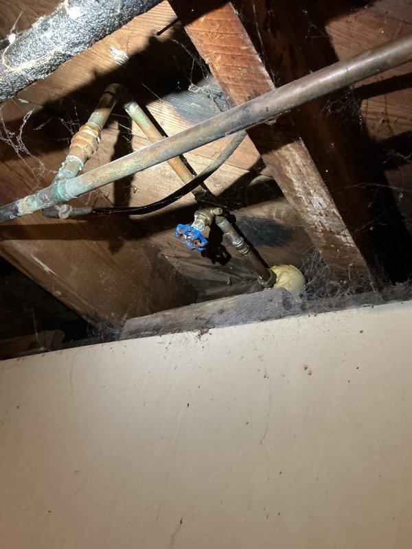 Responded to service call for two non-functional outdoor spigots with active leaks occurring inside the residence. Located leak sources in attic/ceiling cavity where supply lines fed exterior hose bibs. Accessed crawl space and identified failed connections and deteriorated fittings on copper supply lines serving both spigots. Replaced defective ball valve assembly with blue-handled brass valve, repaired compromised pipe connections, and secured all plumbing runs within ceiling framework. Tested system under full pressure to verify leak elimination and restored water service to both outdoor spigots for normal operation.