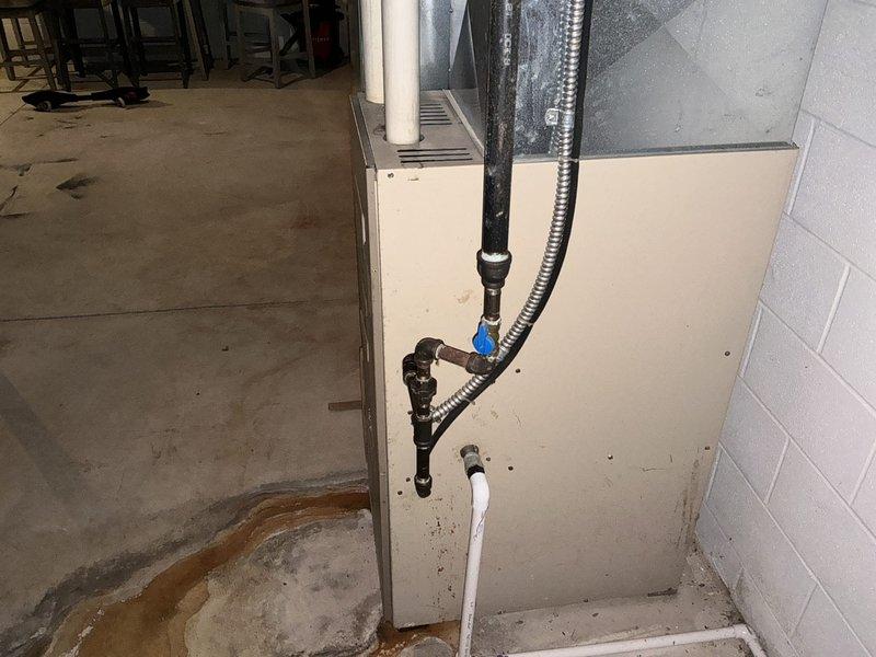 Conducted furnace replacement estimate for Armstrong Air Ultra V unit with reported cracked heat exchanger as identified by previous contractor. Documented existing basement installation including current furnace configuration, ductwork connections, PVC venting system, and surrounding utility equipment including water heater. Noted evidence of previous water damage on concrete floor near equipment area and assessed accessibility for replacement work.