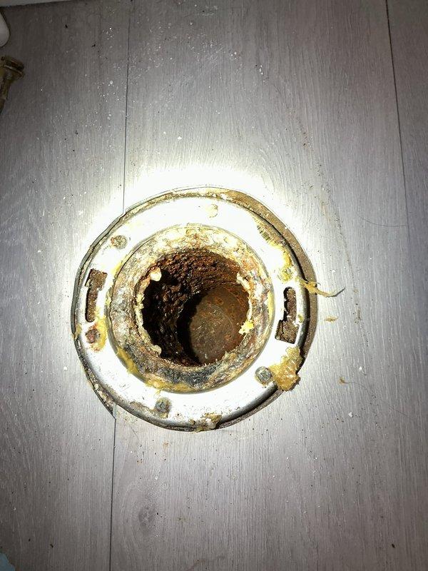 Responded to main drain clog causing water backup in basement. Upon inspection, located heavily corroded floor drain with significant mineral buildup and deterioration at the main drain exit point. Accessed main cleanout assembly, which showed extensive staining and biological growth indicating chronic drainage issues. Cleared blockage from main drain line, restoring proper flow and eliminating standing water condition in basement.