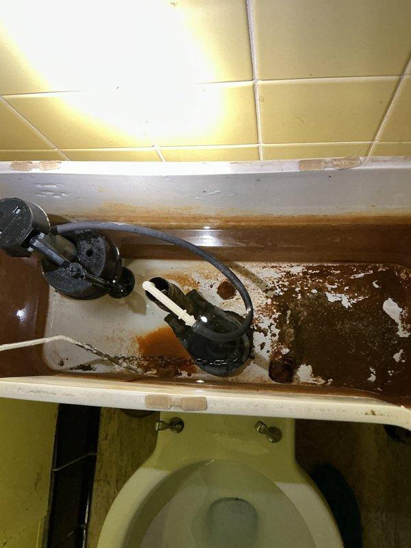 Responded to a toilet repair requiring complete tank overhaul and floor reconnection. Upon arrival, found toilet improperly secured to floor flange and tank components heavily corroded with mineral deposits and rust buildup. Removed toilet in two pieces due to tight workspace constraints in corner installation. Replaced all internal tank components including flush valve, fill valve, flapper assembly, and supply line connections. Cleaned extensive mineral deposits from tank interior. Reset toilet bowl to floor flange with new wax ring and closet bolts, ensuring proper seal and stability. Reconnected tank to bowl with new tank-to-bowl gasket and hardware. Tested flush mechanism and verified no leaks at all connection points.
