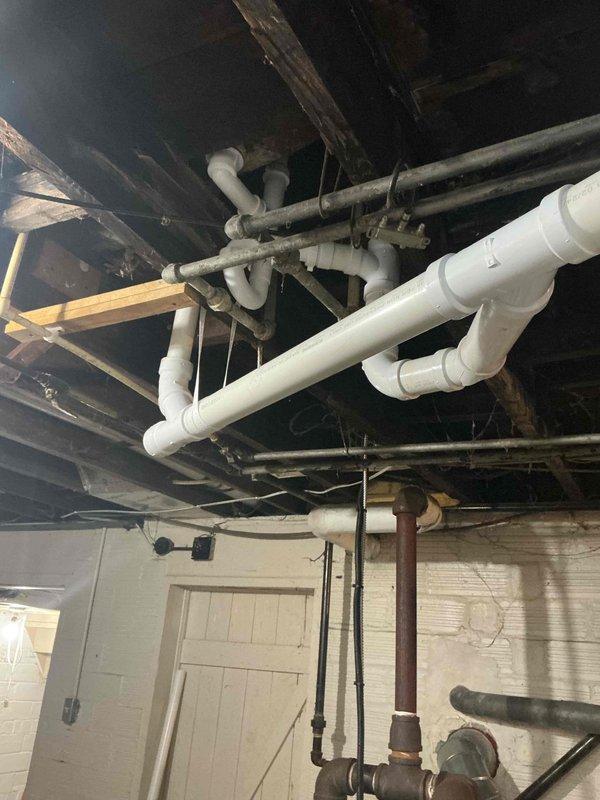 Replaced defective waste and overflow assembly and removed a section of severely deteriorated drain piping in the basement that was actively leaking. Installed new white PVC drainage piping with proper fittings and connections to restore functionality and eliminate water damage. All new plumbing components were secured to existing structural supports and tested for proper drainage flow.