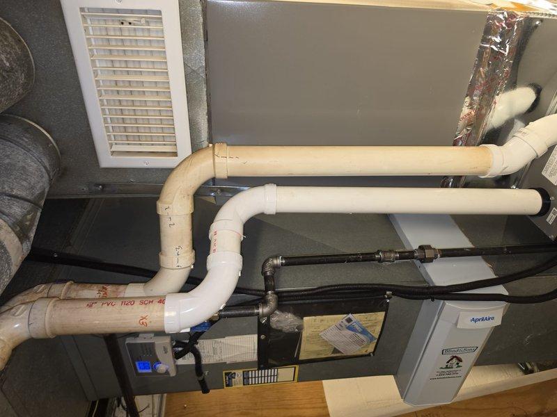 Completed installation of 90% AFUE furnace system in residential utility space. Installed gray metal air handler unit with complete PVC venting system using Schedule 40 pipe, configured condensate drainage lines, and connected refrigerant lines with proper insulation. Integrated Aprilaire humidification system, secured all piping with appropriate mounting hardware, and verified proper clearances per manufacturer specifications.