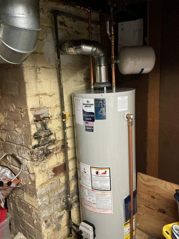 Responded to emergency carbon monoxide leak from tanked water heater. Upon arrival, property was evacuated and emergency services had been contacted. Inspected Bradford White water heater unit and surrounding ventilation system. Found significant dust and lint accumulation on HVAC blower housing and ductwork, which may have contributed to improper ventilation. Examined metallic vent pipe configuration and copper supply lines for proper installation and clearances. Documented equipment condition, including water heater specifications, expansion tank installation, and deteriorated basement wall conditions that showed moisture damage. Photographed all relevant equipment and safety concerns for record and follow-up assessment.
