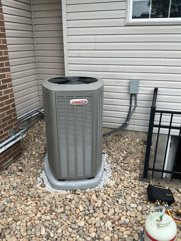 Completed full HVAC system installation including outdoor Lennox condensing unit mounted on concrete pad with proper drainage and rock landscaping. Installed refrigerant lines, electrical disconnect, conduit, and all necessary connections to exterior wall with secure mounting brackets. Verified system performance with temperature differential readings showing 162.9°F, confirming proper operation and heat exchange efficiency.