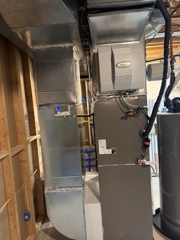 Completed installation of 90% AFUE furnace system in basement utility area. Mounted and connected Aprilaire humidifier unit to furnace, installed black flexible ductwork connections, and configured metal supply ductwork at ceiling level. Established electrical connections including junction box mounting, control wiring, and power supply integration. Installed PVC condensate drainage lines and completed all necessary piping connections for proper system operation. Unit tested and operational.