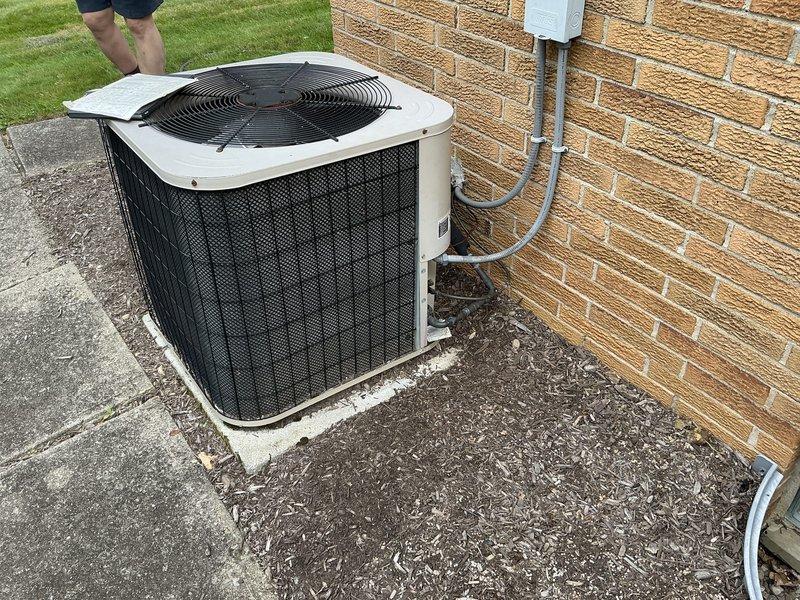 Provided comprehensive estimate for replacement of 18-year-old residential air conditioning system experiencing refrigerant leak and low charge. Evaluated existing outdoor condenser unit positioned on concrete pad against exterior brick wall, assessed property specifications including 1,200 square foot main level, 900 square foot basement, and insulated attic space. Presented equipment options and financing solutions for air conditioning replacement to address aging system and refrigerant loss issues.
