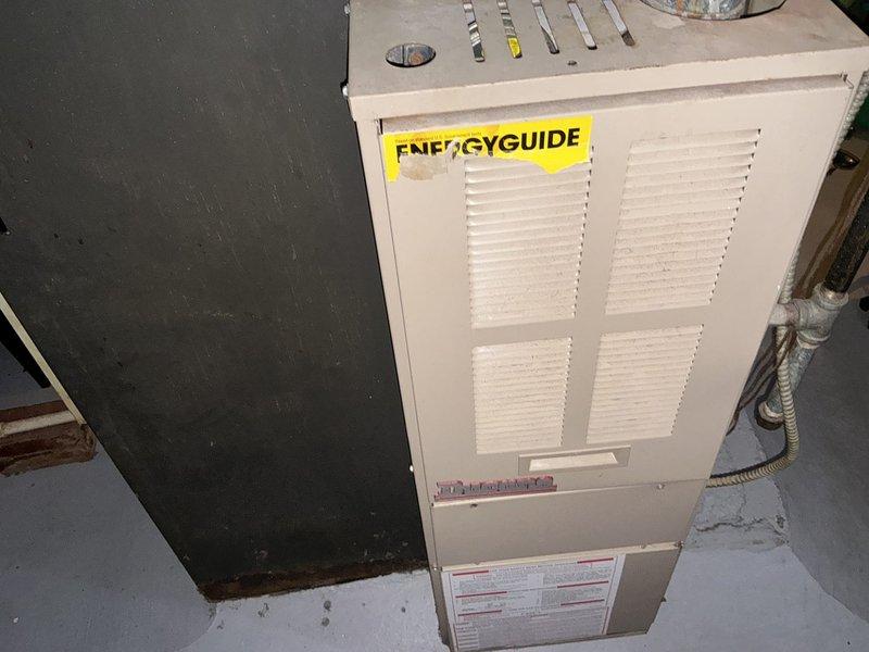 Conducted comprehensive assessment of 29-year-old non-operational furnace and air conditioning system for complete replacement estimate. Previous service provider had diagnosed failed control board and smart valve with repair costs exceeding $1300. Evaluated existing forced air heating system including deteriorated ductwork insulation visible throughout basement area, documented equipment specifications from manufacturer nameplate, and assessed overall system infrastructure. Photographed current equipment condition showing age-related wear, compromised insulation on main trunk lines requiring remediation, and moisture indicators near foundation area. Provided detailed replacement options for both heating and cooling equipment to restore full HVAC functionality to residence. Coordinated availability window with homeowner's work schedule requiring advance notification for installation.