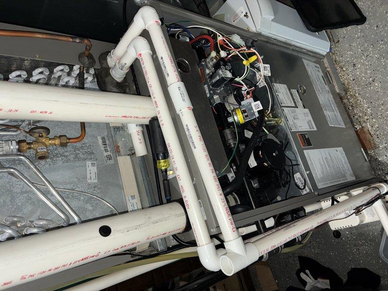 Responded to water leak complaint on 2-year-old Lennox AC unit (EL18XCV-036-230A03). Found condensate catch basin malfunctioning, causing water to discharge from overflow pipe onto floor. Inspected condensate drain system including PVC drainage lines and internal catch pan. Cleared blockage in primary drain line, verified proper pitch and flow through condensate piping, and tested safety float switch operation. Confirmed unit cycling properly with condensate draining correctly through primary line without overflow. System returned to normal operation with no further water leakage observed.