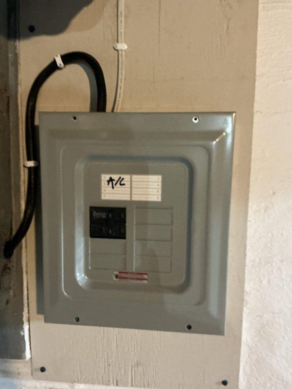 Installed new electrical subpanel with dedicated circuit breaker for air conditioning system. Ran conduit from main service panel, mounted gray metal distribution panel on interior wall, and installed circuit breakers with proper labeling for A/C unit. All work completed to code specifications with secure mounting and proper wire management.