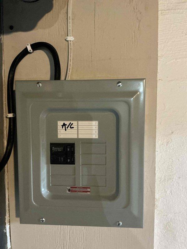 Installed new electrical subpanel with dedicated circuit breaker for air conditioning system. Ran conduit from main service panel, mounted gray metal distribution panel on interior wall, and installed circuit breakers with proper labeling for A/C unit. All work completed to code specifications with secure mounting and proper wire management.