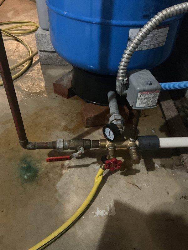 Responded to service call for leaking well pressure tank in basement. Upon arrival, coordinated timing with customer to provide required advance notice. Inspected blue pressure tank system and identified active leak at tank connection points. Assessed complete well water system including pressure tank, pump assembly, brass manifold fittings, shut-off valves, pressure gauge, and associated copper and PVC piping. 

Diagnosed leak source and performed necessary repairs to pressure tank connections and plumbing assembly. Verified all brass fittings, valve connections, and pipe joints for proper seal integrity. Tested system pressure and monitored for any additional leaks. Confirmed pump operation and pressure tank functionality after repairs were completed. Left work area clean and system fully operational.