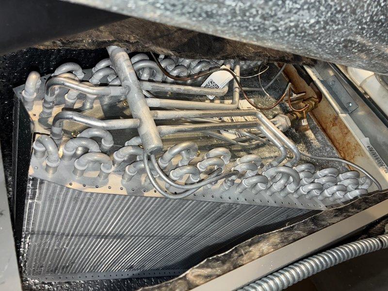 Completed comprehensive cooling maintenance on 8-year-old air conditioning system and furnace. Inspected and photographed air filter showing standard diamond-pattern mesh construction, verified evaporator coil assembly with serpentine refrigerant lines and finned heat exchanger, and documented system components including refrigerant piping with brass fittings. All maintenance procedures performed according to manufacturer specifications with unit operating within normal parameters.