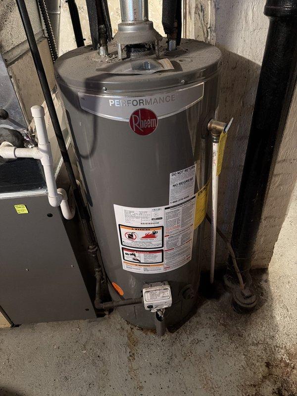 Responded to service call for 8-year-old Rheem Performance tanked water heater with reported leaking at bottom of tank. Upon inspection, confirmed active leak originating from lower section of tank, indicating internal tank failure. Documented existing installation including water supply connections, gas line configuration, flue venting system, and surrounding mechanical equipment. Leak at tank bottom is characteristic of sediment buildup and internal corrosion common in units of this age, requiring full water heater replacement as tank leaks cannot be repaired.