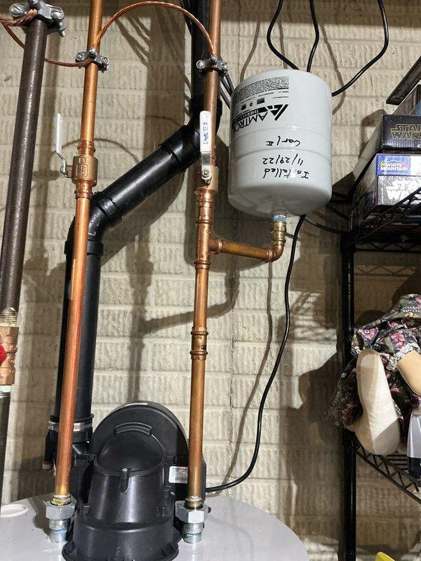 Responded to service call for leaking water heater. Upon arrival, confirmed leak originating from tank connections and assessed plumbing assembly including copper piping, brass fittings, and shutoff valves. Inspected water heater installation, surrounding plumbing components, and utility area for water damage. Documented existing conditions with photographs showing water heater configuration, pipe connections, and affected floor area beneath unit.