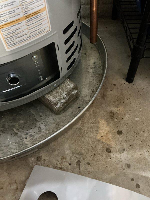 Responded to service call for leaking water heater. Upon arrival, confirmed leak originating from tank connections and assessed plumbing assembly including copper piping, brass fittings, and shutoff valves. Inspected water heater installation, surrounding plumbing components, and utility area for water damage. Documented existing conditions with photographs showing water heater configuration, pipe connections, and affected floor area beneath unit.