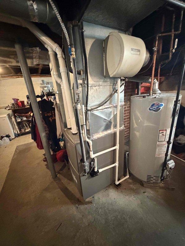 Completed installation of 90% AFUE furnace system in basement utility space. Installed new furnace unit with proper clearances adjacent to existing water heater, integrated horizontal-mounted humidifier system, and connected all necessary PVC venting, copper refrigerant lines, and supply/return ductwork. System tested and verified operational with all safety controls functioning properly.