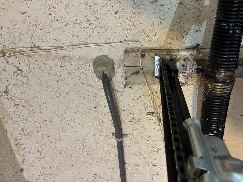 Installed exterior floodlight with dusk-to-dawn photocell sensor above garage center to illuminate driveway. Sourced power from attic circuit, ran surface-mounted sealant-rated conduit down exterior wall, and terminated into weatherproof round bell box for fixture mounting. Completed installation with all components secured and operational.