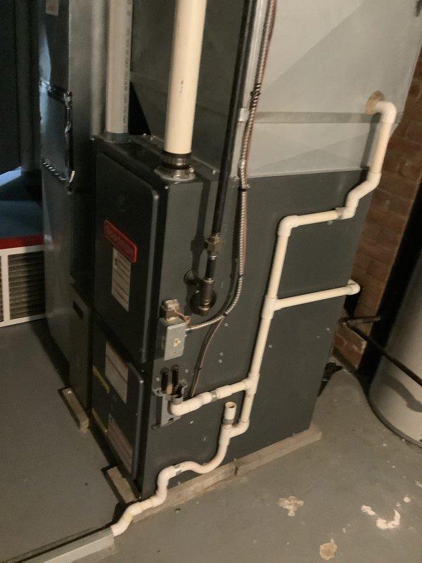 Performed comprehensive evaluation of existing HVAC system after identifying a cracked heat exchanger in the furnace unit. Documented current equipment configuration including the furnace and air conditioning system installed in the basement utility area. Assessed the dark-colored furnace unit with associated white PVC venting and condensate drainage piping, along with the connected cooling equipment. 

Due to the failed heat exchanger posing safety concerns, provided detailed replacement estimates for complete system upgrade. Quoted two equipment options: a 22 SEER rated system and a 24 SEER rated high-efficiency system to replace both the furnace and air conditioning units. Photographed existing installation showing current equipment placement against the exposed brick wall, PVC vent piping configuration, flexible metal conduit routing, and concrete floor conditions to document pre-replacement status and facilitate accurate sizing for new equipment installation.