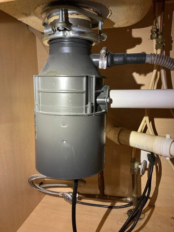 Removed and replaced failed garbage disposal unit with customer-supplied unit. Disconnected existing disposal from sink mounting assembly, electrical connection, and drain lines. Installed new disposal unit, securing mounting flange to sink drain opening, connecting dishwasher drain line with hose clamp, and attaching discharge pipe to existing drain system. Restored electrical power and tested unit for proper operation and verified no leaks at connections.