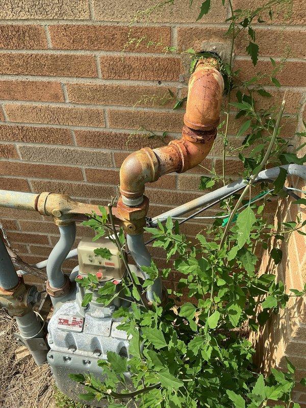 Responded to service call for gas line extension quote. Inspected existing natural gas meter installation mounted on exterior brick wall, noting current copper and steel piping configuration with brass fittings. Assessed routing requirements for extending gas line from ground-level meter assembly vertically to roof location. Documented existing infrastructure including weathered copper riser, painted steel distribution lines, and meter connections. Photographed current gas meter setup and building exterior to determine optimal routing path and material requirements. Evaluated wall structure, pipe clearances, and accessibility for future installation work. Provided customer with detailed assessment and prepared quote for gas line extension to roof as requested.