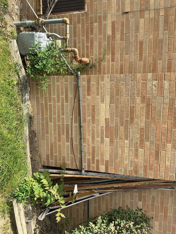 Responded to service call for gas line extension quote. Inspected existing natural gas meter installation mounted on exterior brick wall, noting current copper and steel piping configuration with brass fittings. Assessed routing requirements for extending gas line from ground-level meter assembly vertically to roof location. Documented existing infrastructure including weathered copper riser, painted steel distribution lines, and meter connections. Photographed current gas meter setup and building exterior to determine optimal routing path and material requirements. Evaluated wall structure, pipe clearances, and accessibility for future installation work. Provided customer with detailed assessment and prepared quote for gas line extension to roof as requested.